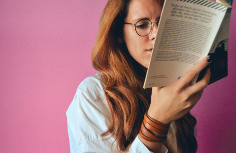 Young woman wearing glasses reading a book.